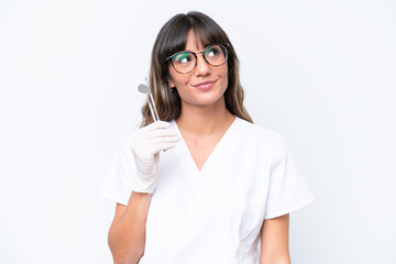 Dentist caucasian woman holding tools isolated on white background thinking an idea while looking up