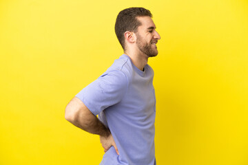 Handsome blonde man over isolated yellow background suffering from backache for having made an effort