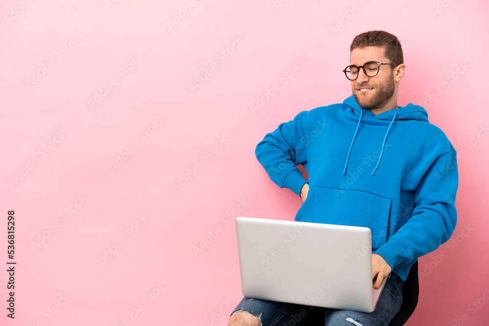 Sticker Young man sitting on a chair with laptop suffering from backache for having made an effort