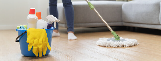 happy Female housekeeper service worker mopping living room floor by mop and cleaner product to...