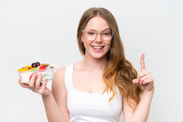 Young pretty woman holding a bowl of fruit isolated on white background pointing up a great idea