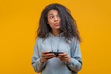 Studio portrait of cute coquette casually dressed girl posing with a mobile phone in hands isolated...
