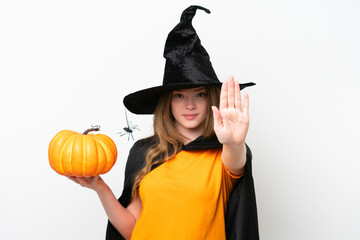 Young pretty woman costume as witch holding a pumpkin isolated on white background making stop gesture