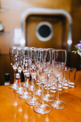 A lot, a row of empty transparent expensive wine glasses stands on a wooden table in a bar, cafe close-up.