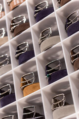 Various coloured leather belt display on shelf in the store in a men clothing boutique.