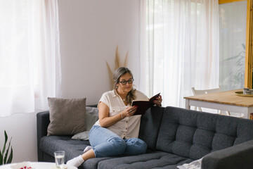 Lifestyle portrait of woman reading a book at home