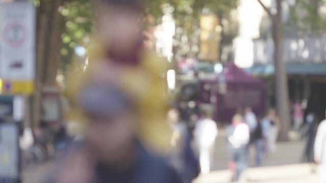 Blurred background of daytime shoppers walking around a town centre, in slow motion