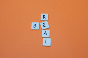 Be real text with plastic letters on orange paper sheet. Popular and trendy mobile app called Be Real is spreading around the globe. Be realistic yourself is a good way of living your life.