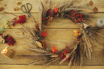 Stylish autumn wreath on rustic table flat lay. Rustic autumn wreath with dried grass, berries,...