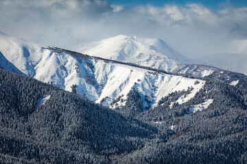 Snow covered mountain peaks in the clouds