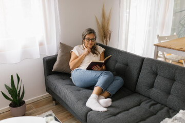 Obraz premium Woman reading a book at home