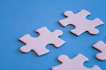 White jigsaw puzzle pieces on blue background with limited close up focus.