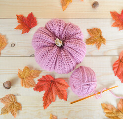 woolen crochet pumpkins on wooden ground, with crochet hooks and autumn leaves