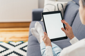 woman with pc tablet in hands on sofa indoors