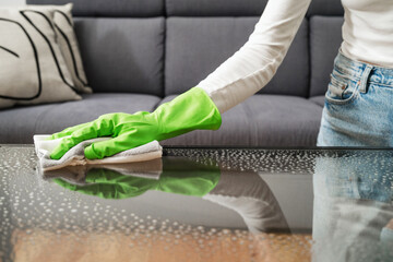 woman with cloth napkin cleaning glass table indoors, closeup