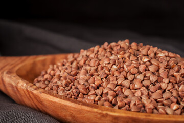 Dry buckwheat groats on wooden spoon.