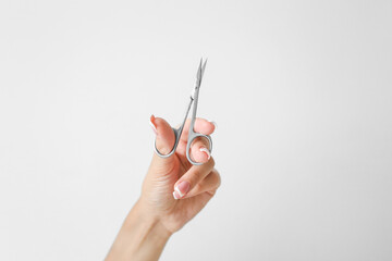 Girl with beautiful long nails hold scissors for manicure on a white background