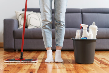 female with mop and bucket with cleaning supplies on floor indoors