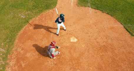OVERHEAD Batter baseball player hits a ball over a home plate - obrazy, fototapety, plakaty