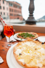 Delicious cheesy italian national pizza with aperol in a restaurant outdoors, a trip to italy. Autumn vacation in Veranzio. Delicious Italian food