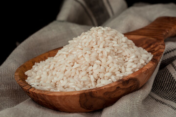 Rice in wooden spoon on kitchen table
