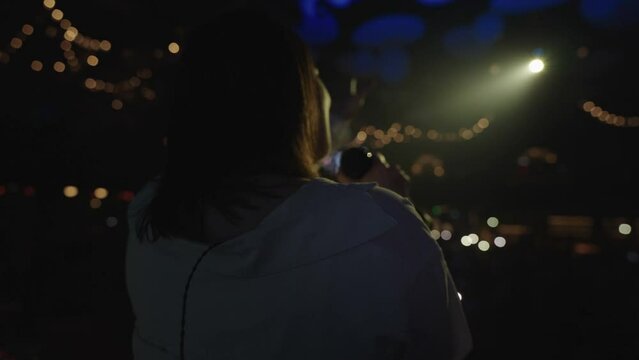 woman singer is singing lyric song on stage in dark music hall, rear view of emotional female musician