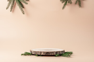 Wooden podium with branches of green spruce  at beige background. Concept scene stage showcase,...