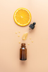 Cosmetic organic, vitamin C extract. Slice of  orange and serum dropper bottle on beige background,...