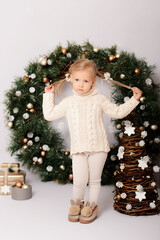 Luxurious Christmas decoration. Merry Christmas and Happy New Year. Little girl at the Christmas wreath with gifts.