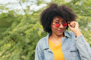 Afro woman posing outdoors with green plants in the background