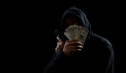 hands of a man wearing a black shirt, sitting on a chair and a table, is a thief, holding money,...