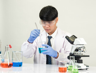 Asian male student scientist in reagent mixing laboratory In a science research laboratory with...
