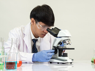 Asian male student scientist in reagent mixing laboratory In a science research laboratory with...