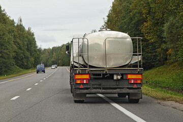 Milk barrel truck drive on countryside road . Liquid food goods delivery