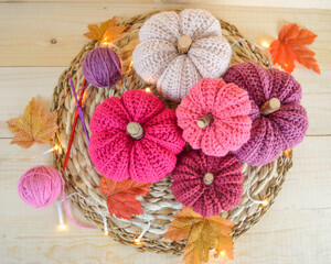 colorful woolen crochet pumkins on wooden ground with crochet hooks, woolen balls and autumn leaves