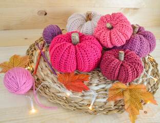 colorful woolen crochet pumkins on wooden ground with crochet hooks, woolen balls and autumn leaves