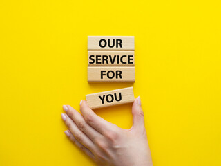 Our service for you symbol. Wooden blocks with words Our service for you. Beautiful yellow background. Businessman hand. Business and Our service for you concept. Copy space.