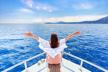 Free carefree satisfied happy inspired traveler girl with open arms enjoys relaxing vacation on a white private boat in turquoise sea