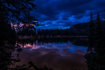 Alta Lake Colorado near Telluride during a blue hour sunset with cloudy sky and forest or trees mirrored reflection in the water 