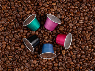 Five coffee capsules on a heap of coffee beans