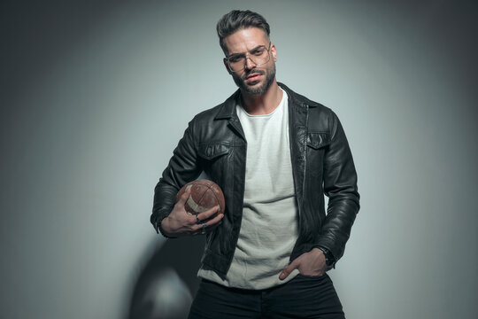 model holding a rugby ball and one hand in pocket