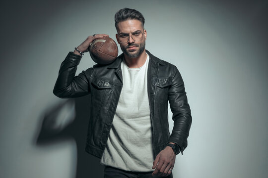 fashion model holding a rugby ball on his shoulder