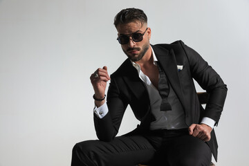 stylish businessman in tuxedo with open collar shirt posing