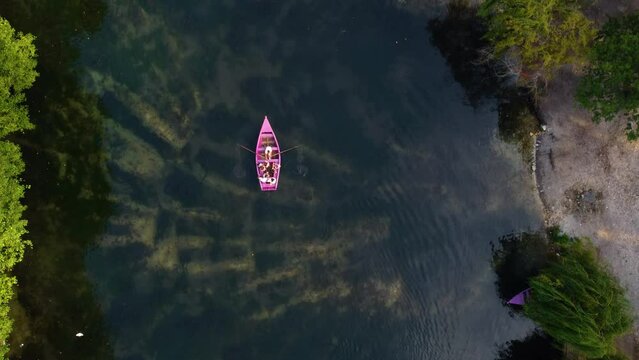 Aerial view of people rowing a pink boat on the lake of Pogradec