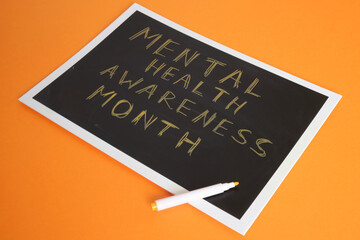 mental health awareness month text on board, orange background