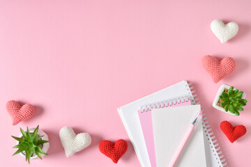 Top view of the office desk. Romantic atmosphere. A notebook with hearts and a pen.