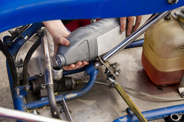 A child pours car oil into a go-kart machine