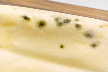 part of a pack of spoiled butter with mold on a wooden board