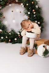 Christmas celebration. Little girl at the Christmas wreath with gifts.  Cute girl in a Christmas...
