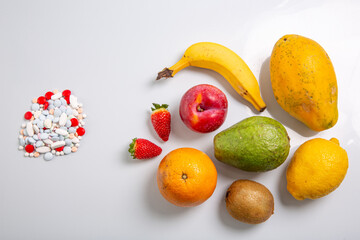 a handful of pills next to a bunch of fresh berries
